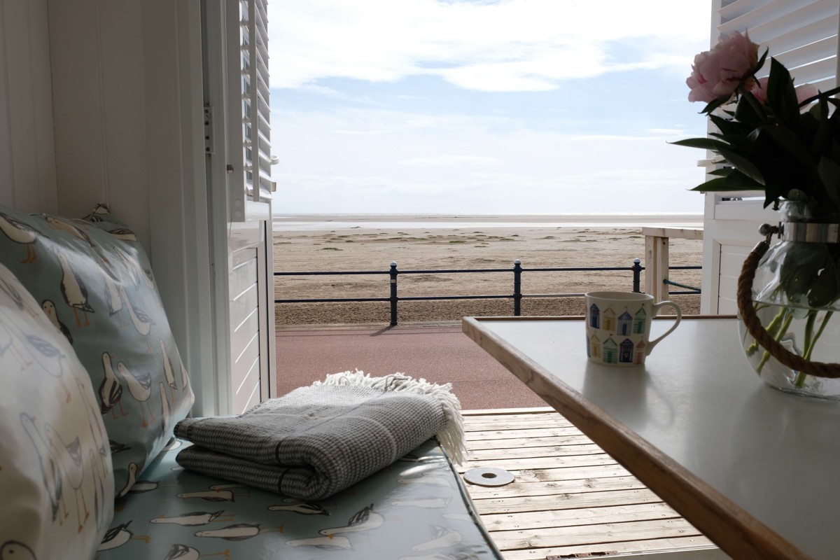 A mug and folded blanket inside a Beach Hut overlooking St Annes beach