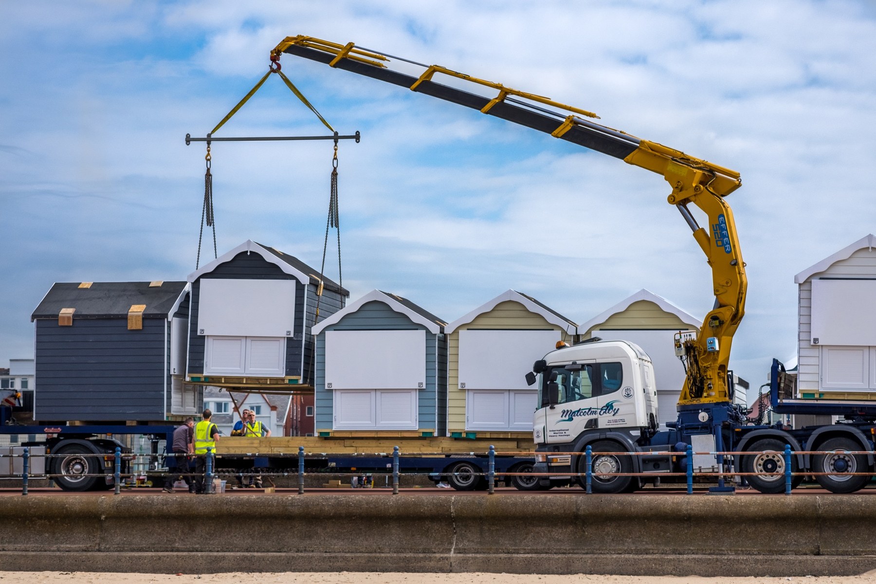 A crane lowering a new Beach Hut into place on the promenade