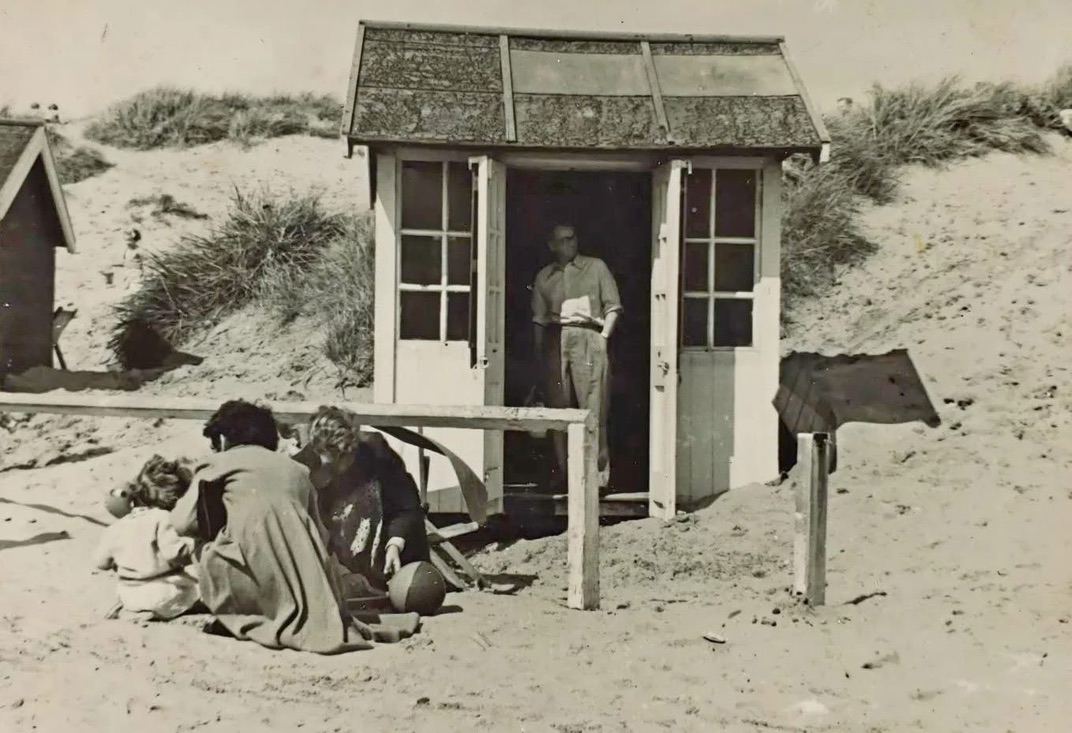A family beside a beach hut among the dunes