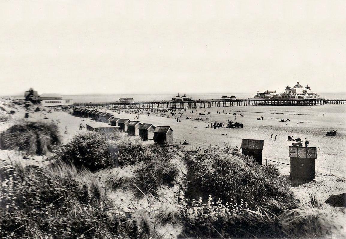 Beach huts among the dunes with the pier beyond