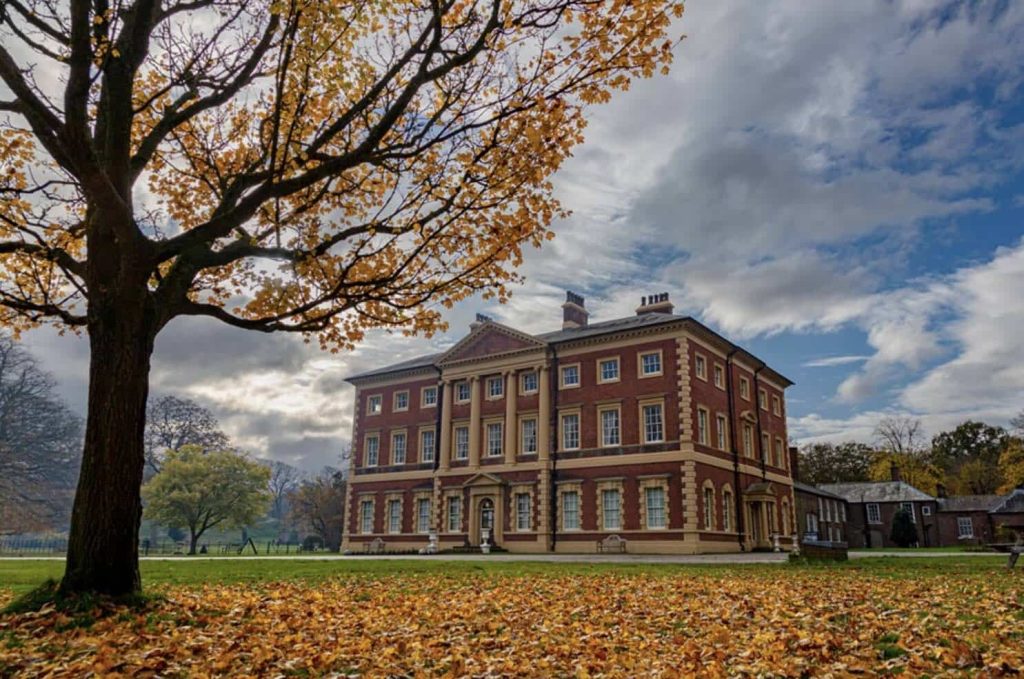 Lytham Hall framed by autumn trees and fallen leaves